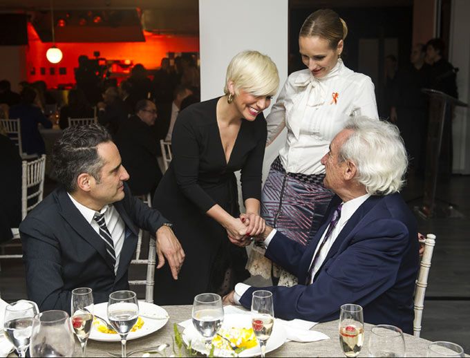 Dos hombres y dos mujeres en una mesa, uno de ellos es Jorge Drexler. Todos ríen y se dan la mano.