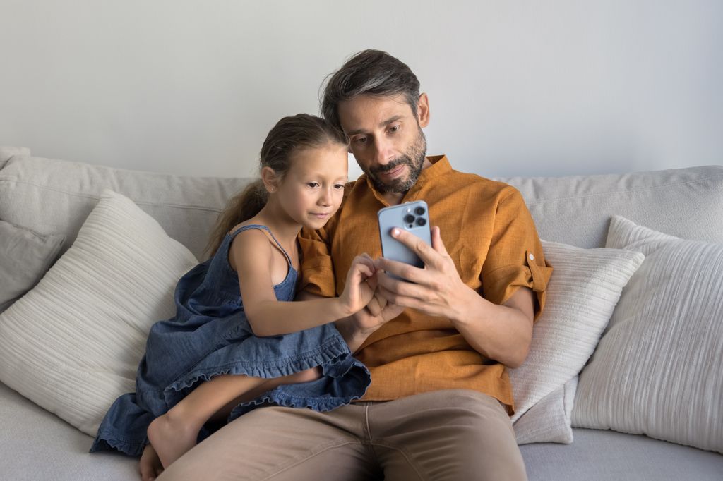 Padre e hija utilizando juntos un móvil