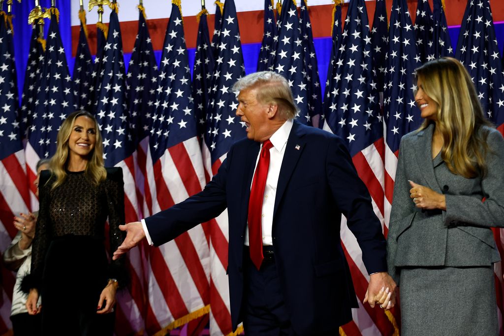 Plano medio de Lara, Donald y Melania Trump en el escenario tras las elecciones