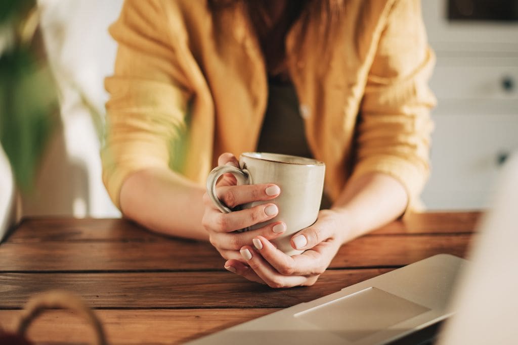 manos de mujer sosteniendo una taza de café