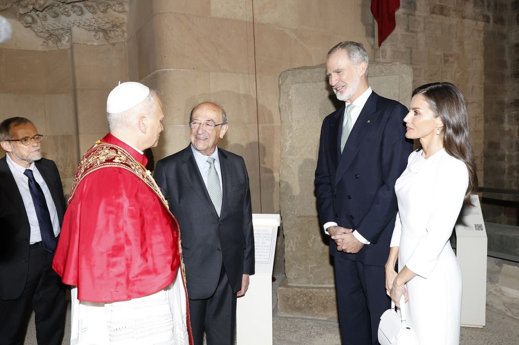 Felipe VI y Letizia de España conversan con un sacerdote y dos hombres en traje.