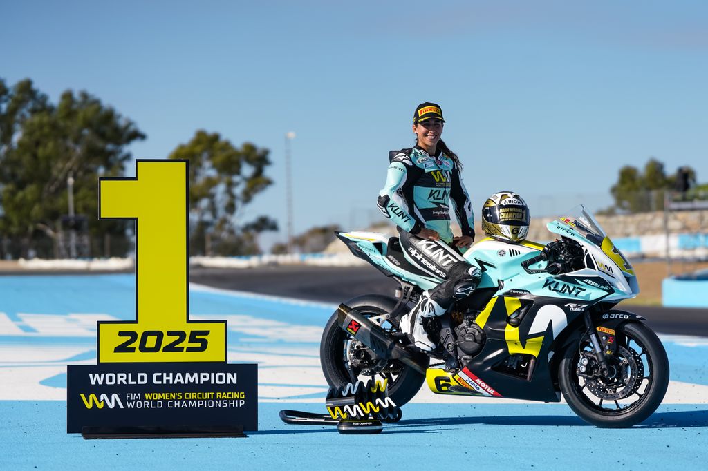 María Herrera posa junto a su moto y su casco dorado tras alzarse con el primer puesto del campeonato mundial de motociclismo femenino