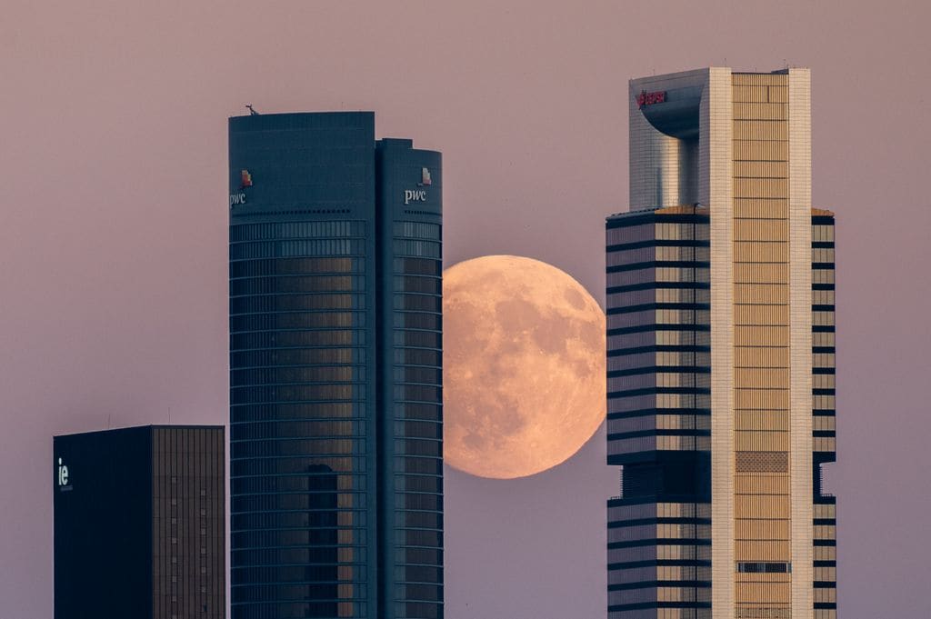 La Luna del Esturión se alza imponente sobre las Cuatro Torres de Madrid, tiñendo el skyline con su brillo casi pleno en una noche de agosto