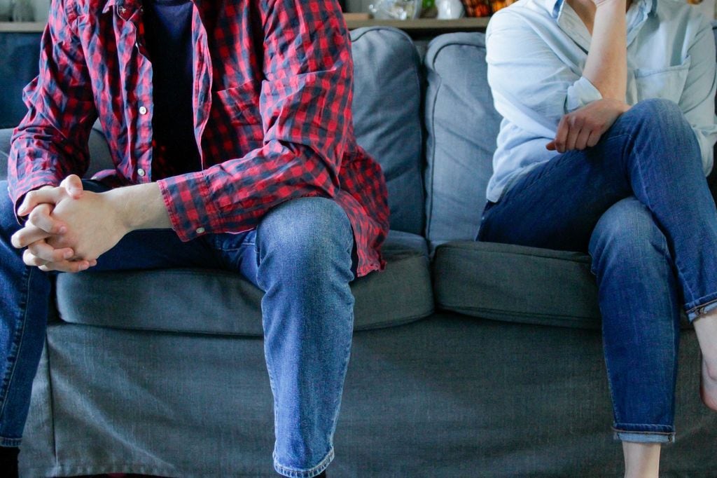 Una pareja sentada en el sofá en actitud enfadada