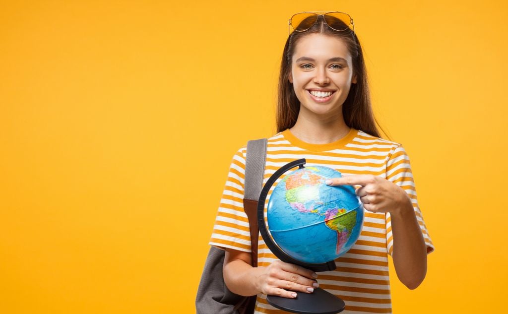 Estudiante europea señalando en globo terráqueo dónde va a estudiar en el extranjero