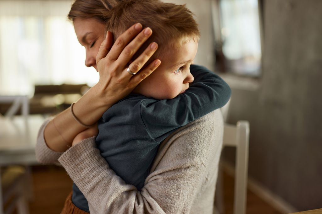 Madre abrazando a su bebé en postura de protección