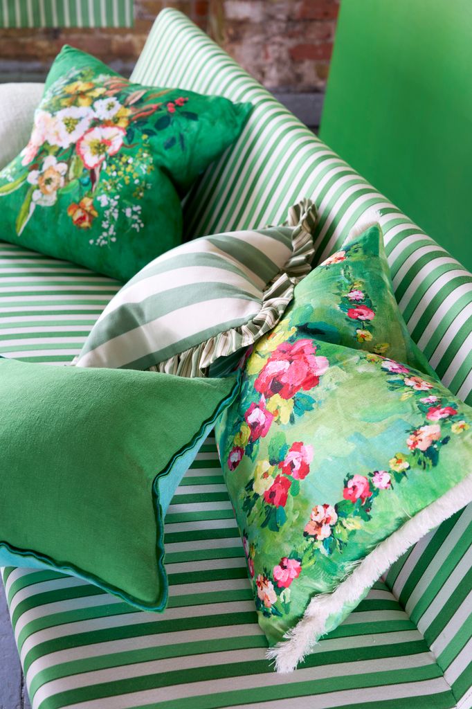 Sofá verde con cojines lisos y estampados en la gama