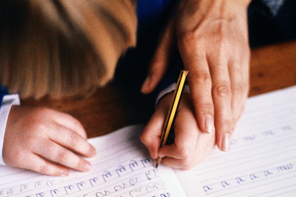 Niño aprendiendo a escribir con la guía de un adulto
