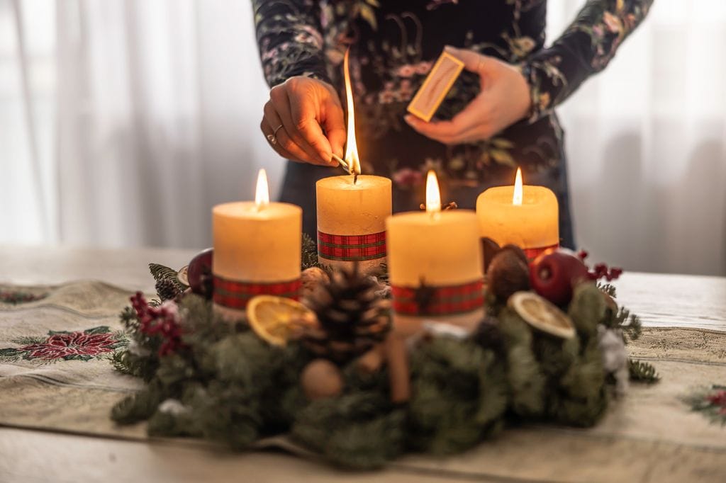 Una corona de Adviento iluminada por velas blancas, que representa la luz de Jesús y el comienzo de la Navidad