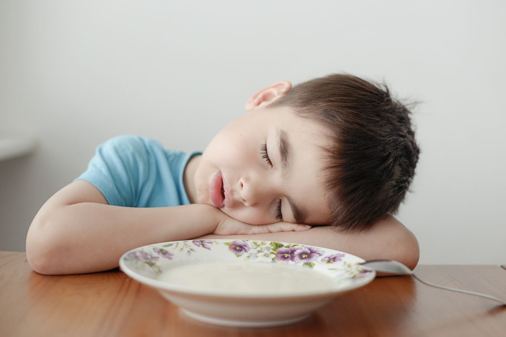 Niño pequeño dormido delante de un plato de comida