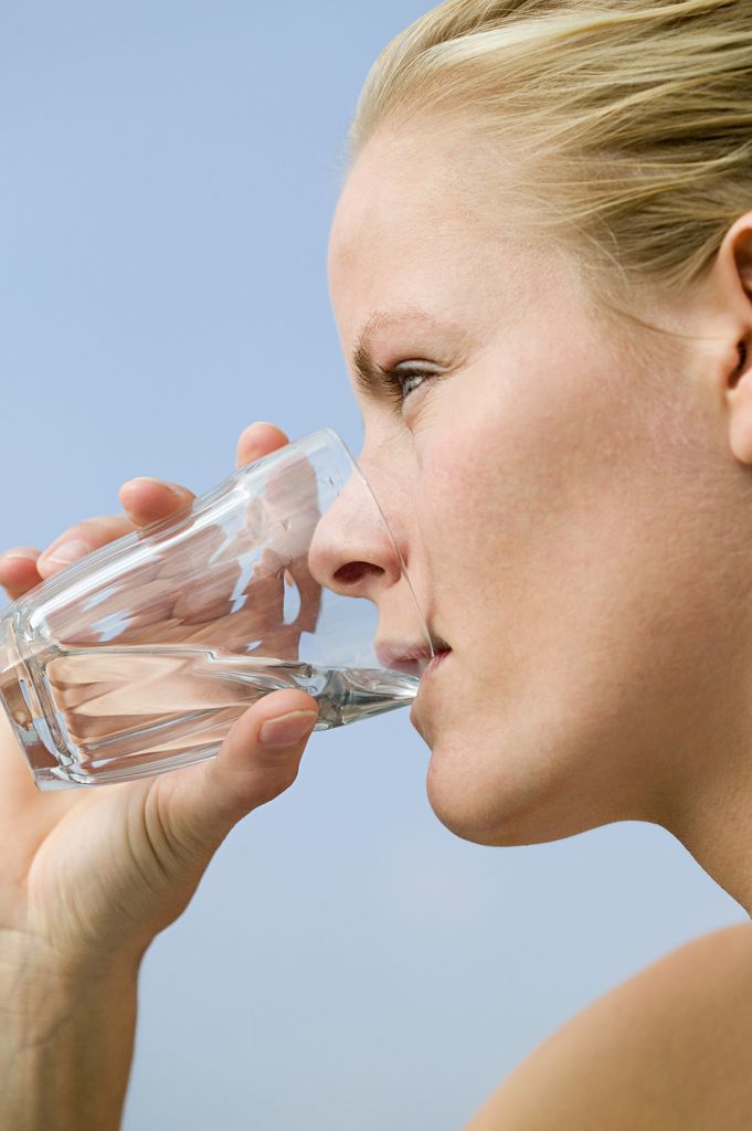 Mujer rubia fondo azul vaso agua