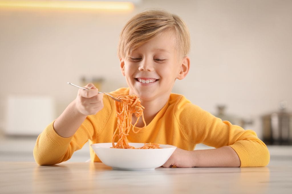 Niño con diabetes comiendo plato de pasta