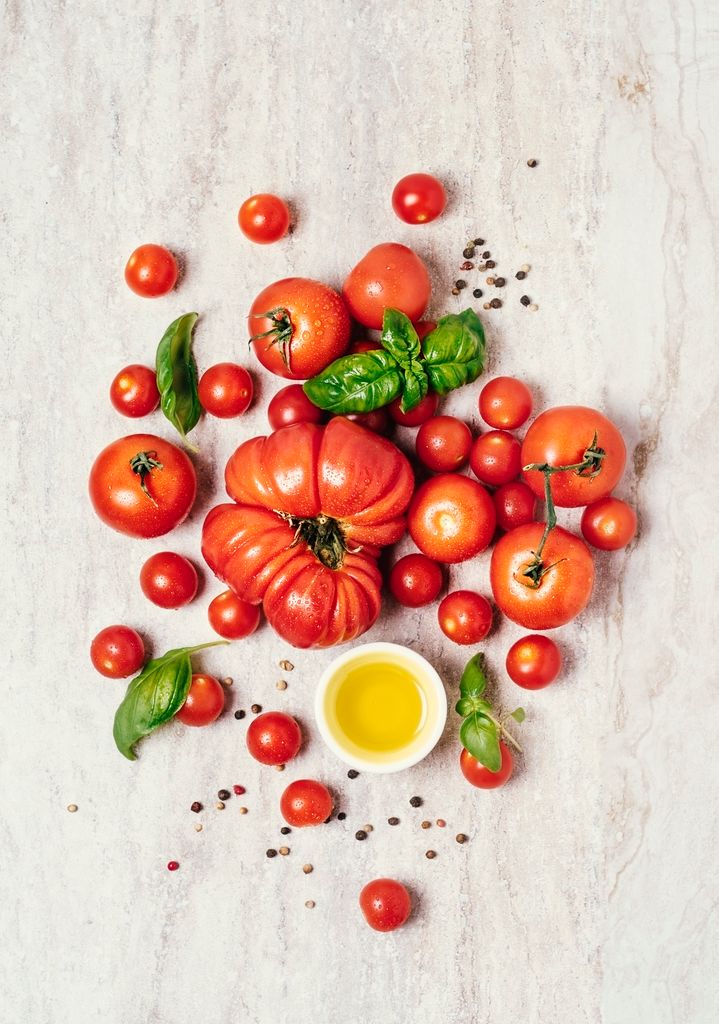 Variety of fresh tomatoes on white, stone background