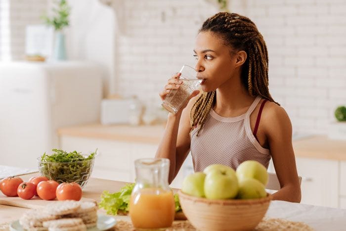 mujer bebiendo agua en la cocina