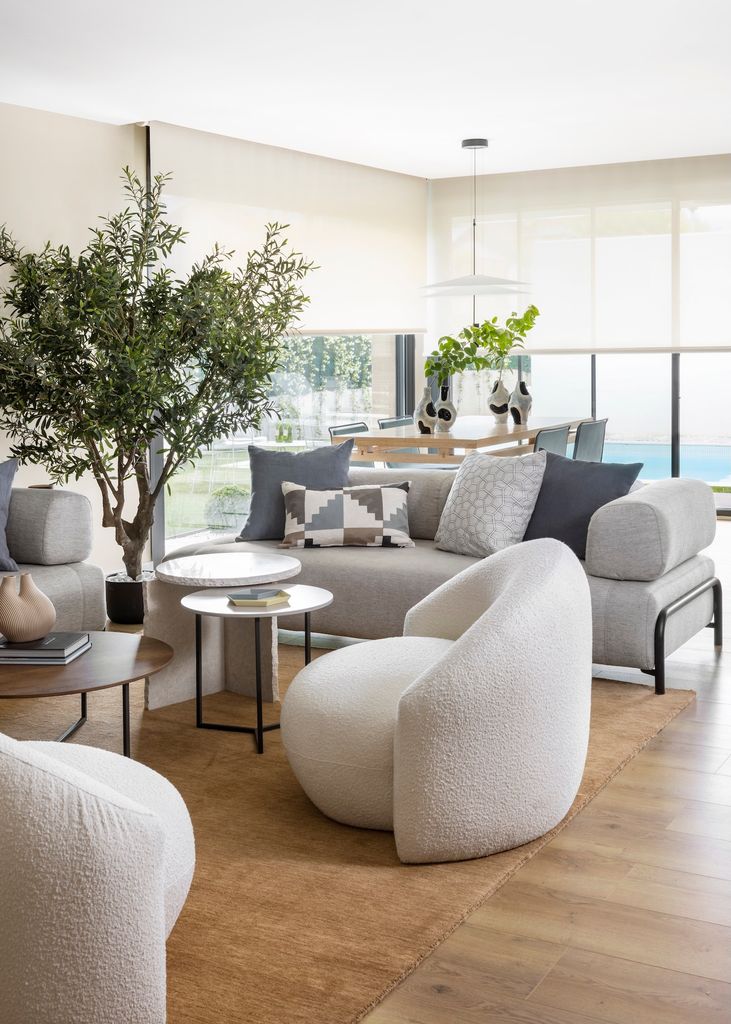 Salón con butacas blancos y sofás grises.