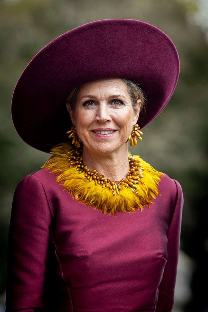 La reina Máxima de Holanda en Omán con collar de plumas amarillo.