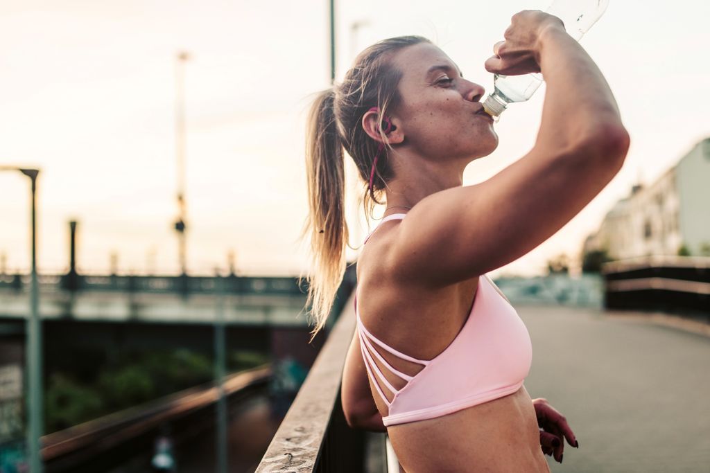 Mujer joven después de correr bebiendo agua