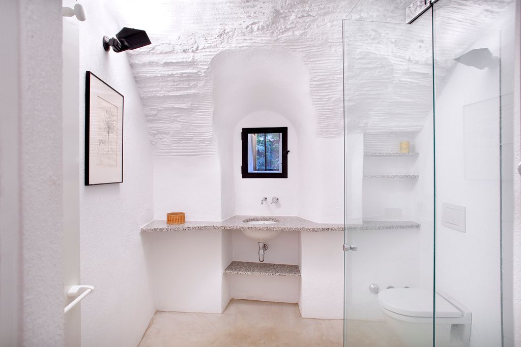 Baño blanco con encimera volada y pared curva
