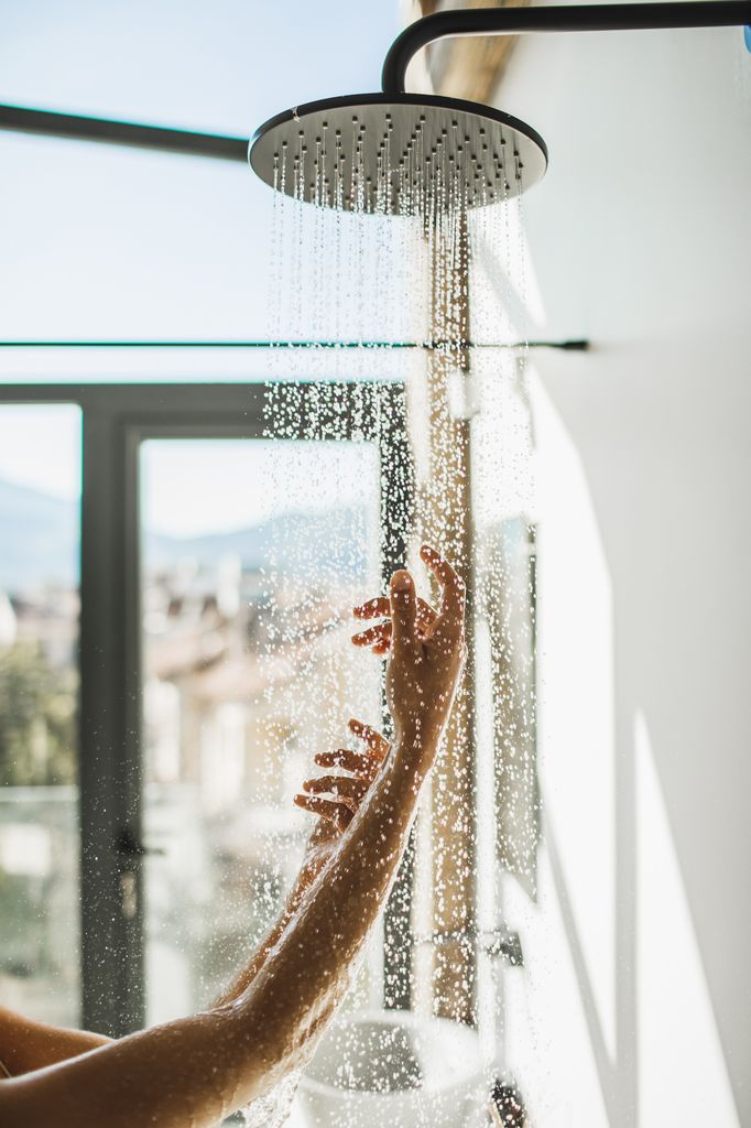Mujer tomando una ducha fría para empezar el día con energía