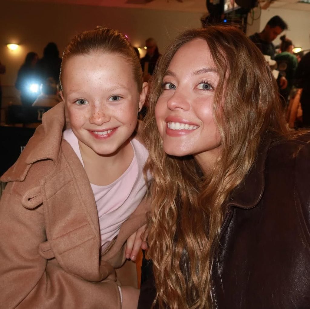 Sydney Sweeney sonriente con ondas suaves y maquillaje natural