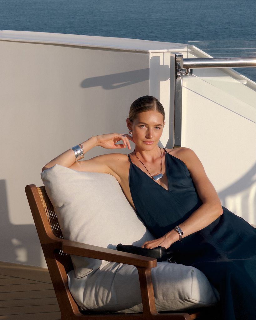 Sanne Vloet sentada en un sillón de un barco con vestido azul marino