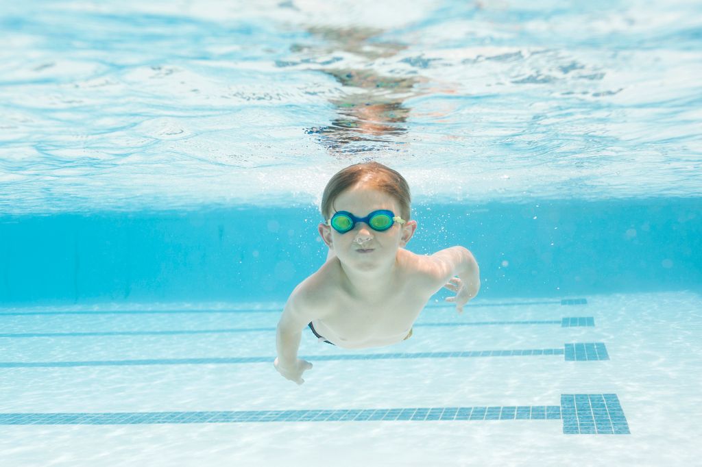 Niño pequeño practicando natación en piscina