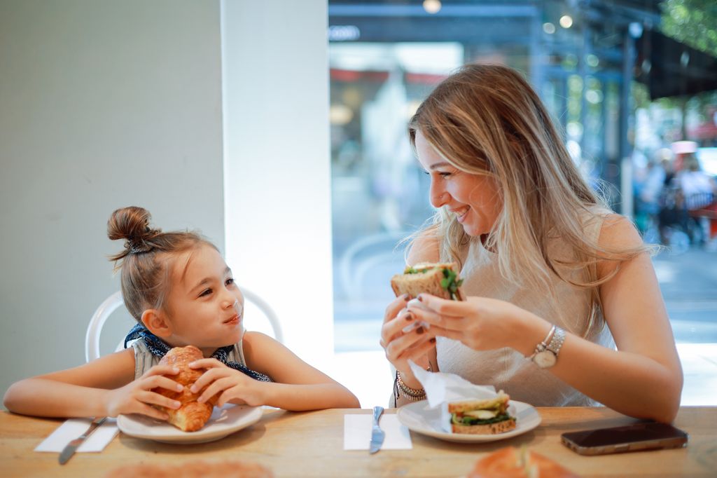 madre e hija disfrutando mientras comen fuera de casa