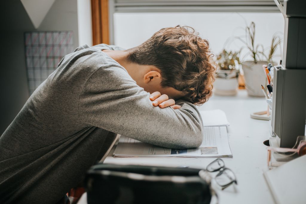 estudiante cansado apoyando su cabeza en los libros