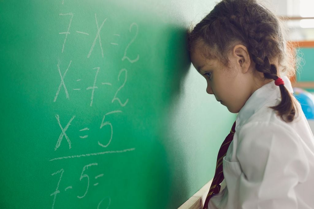 Niña con la cabeza en la pizarra, en contexto de fracaso escolar o repetición de curso