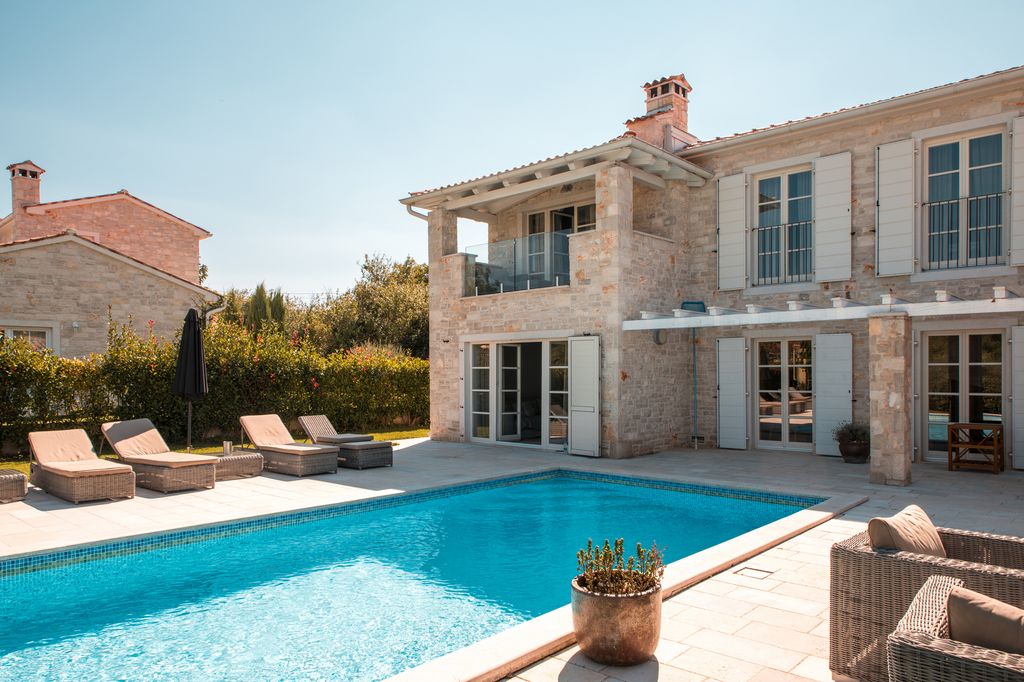 Villa de piedra en el Mediterráneo con piscina, terraza sombreada y mobiliario de fibras naturales: un ejemplo de diseño pensado para el descanso y el confort en climas cálidos