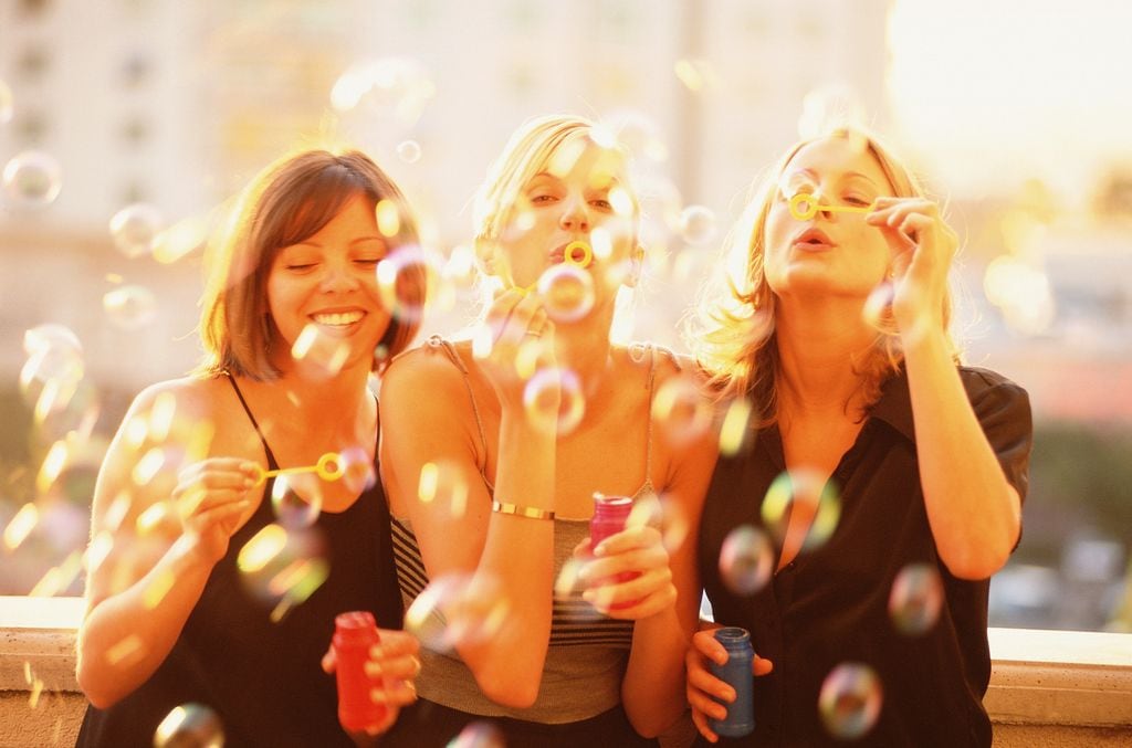 Mujeres amigas jugando haciendo pompas de jabón y divirtiéndose