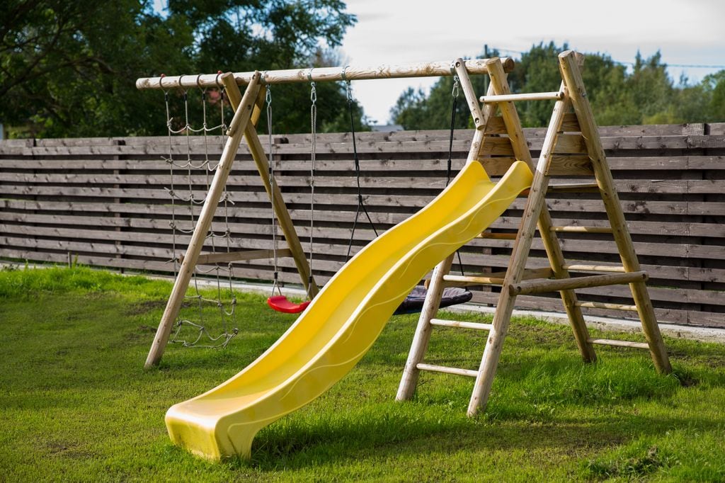 Césped en un jardín, ideal para disfrutarlo descalzo, también columpio y tobogán para el juego y la diversión