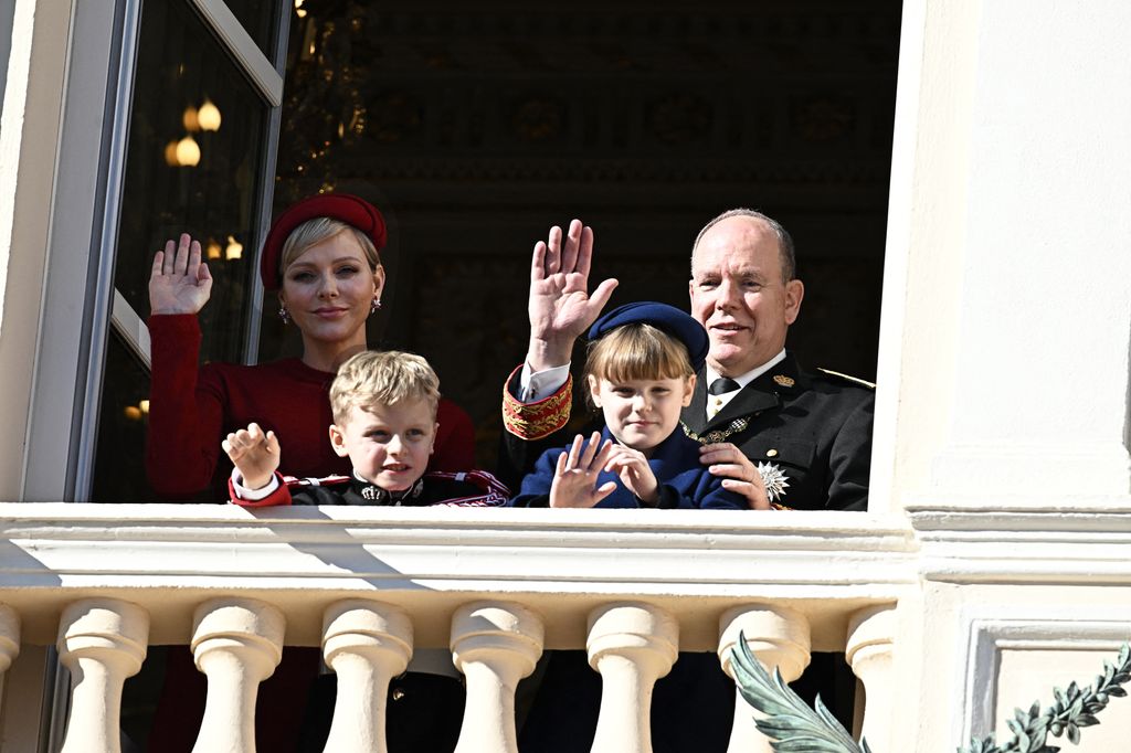 Plano medio de Charlene, Alberto, Jacques y Gabriella de Monaco saludando desde el balcón real