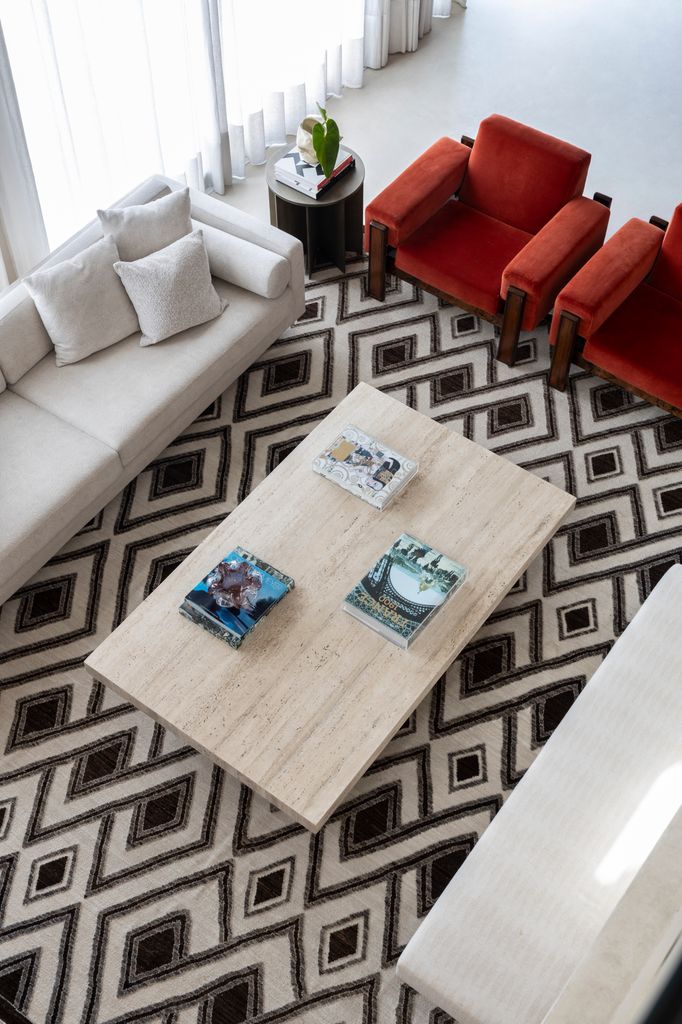 Zona de estar con sofá blanco y butacas de color rojo