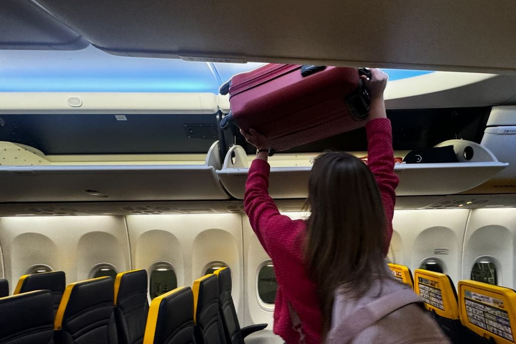 Persona colocando equipaje en el compartimento del avión