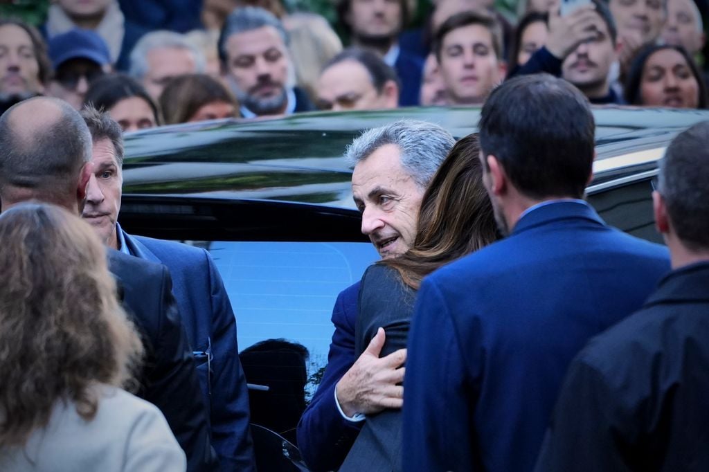 PARIS, FRANCE - OCTOBER 21: Former French president Nicolas Sarkozy embraces his wife Carla Bruni Sarkozy before he steps into the car that will transport him to the Prison de la Sante for a 5 year prison sentence on October 21, 2025 in Paris, France. The former French president (2007 and 2012) will serve five years for criminal conspiracy in SantÃ© prison, Paris, over a scheme to obtain election campaign funds from the regime of the late Libyan dictator Colonel Gaddafi. Sarkozy is the first former head of an EU country to serve time in prison, and the first French postwar leader to be jailed. His son, Louis, has organised a party of well wishers to see his Father off from their home. (Photo by Remon Haazen/Getty Images)