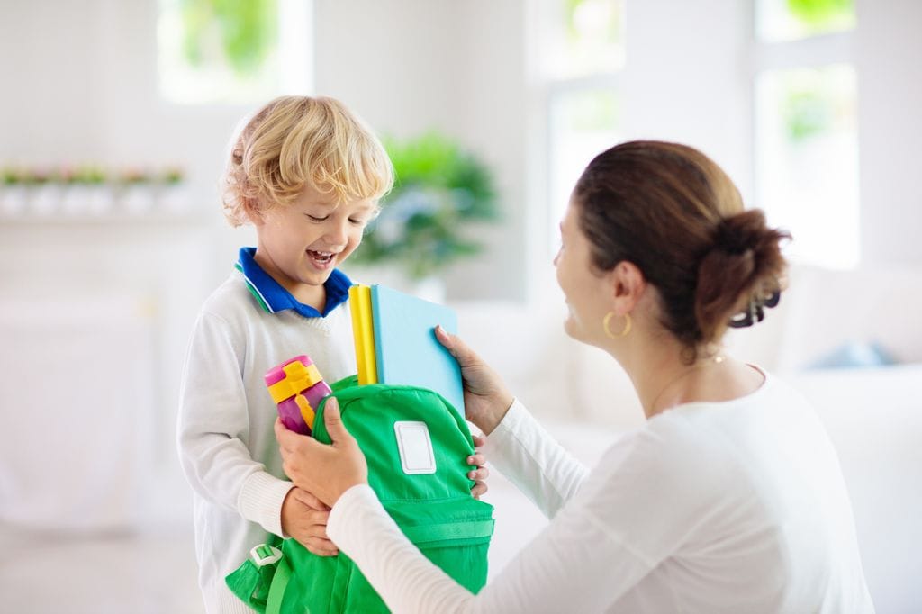 Madre con su hijo pequeño preparando la mochila del colegio