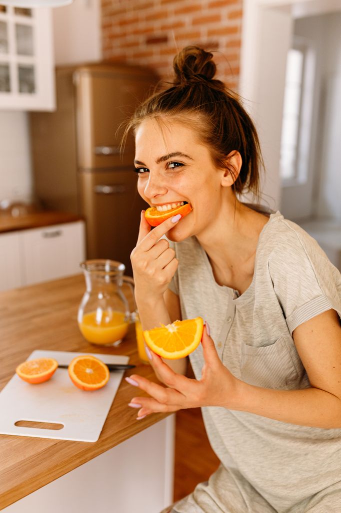 mujer comiendo naranja en la cocina