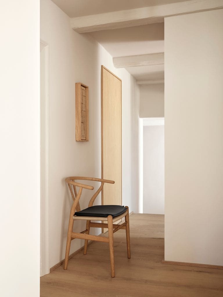 Silla CH24 apoyada en pared del pasillo