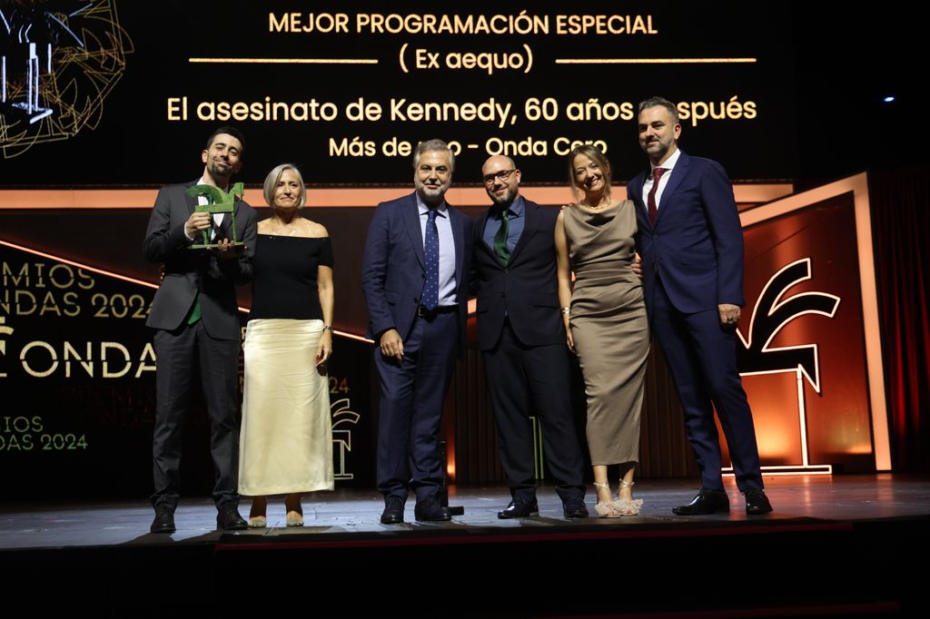 Plano entero de Carlos Alsina con algunos compañeros recibiendo un premio