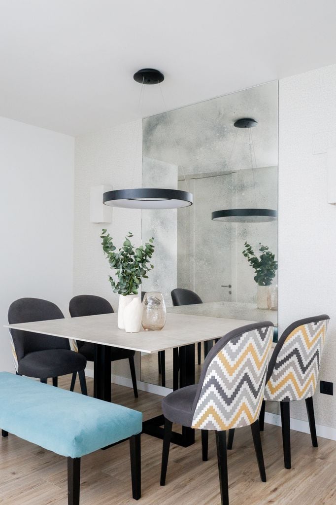 Comedor pequeño que amplía visualmente el espacio con el empleo de un espejo mural