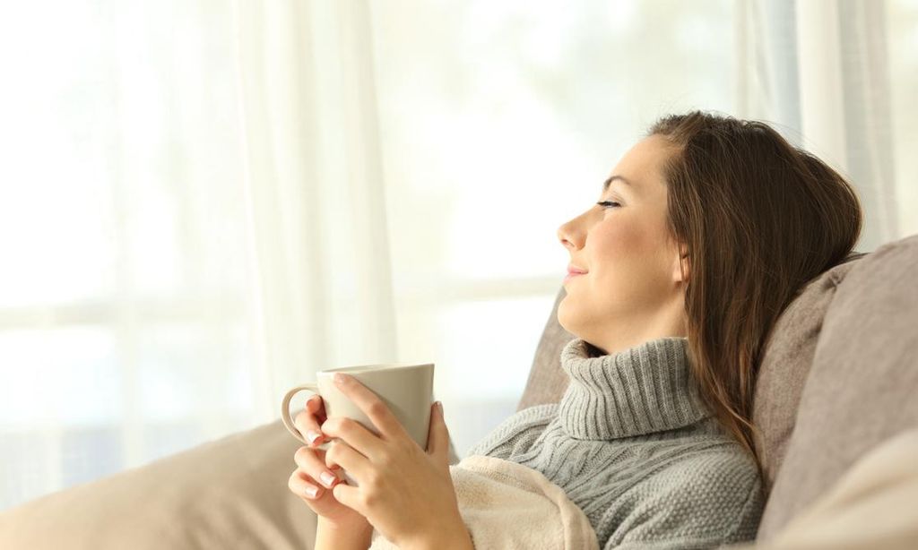 mujer descansa y toma t en un sof 