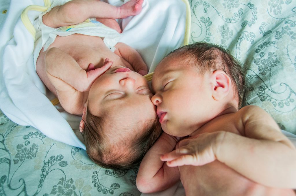 Bebés gemelos tocándose la cara