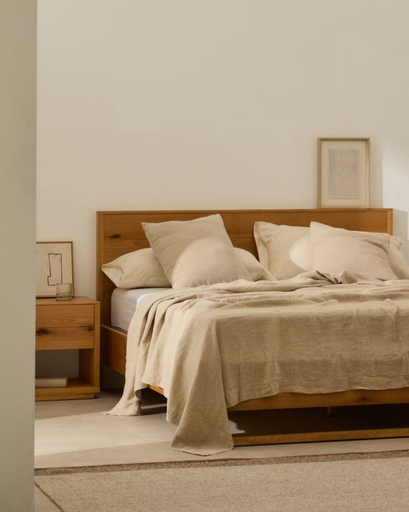 Dormitorio con muebles de madera y textiles de lino de Kave Home todo en tonos tierra.