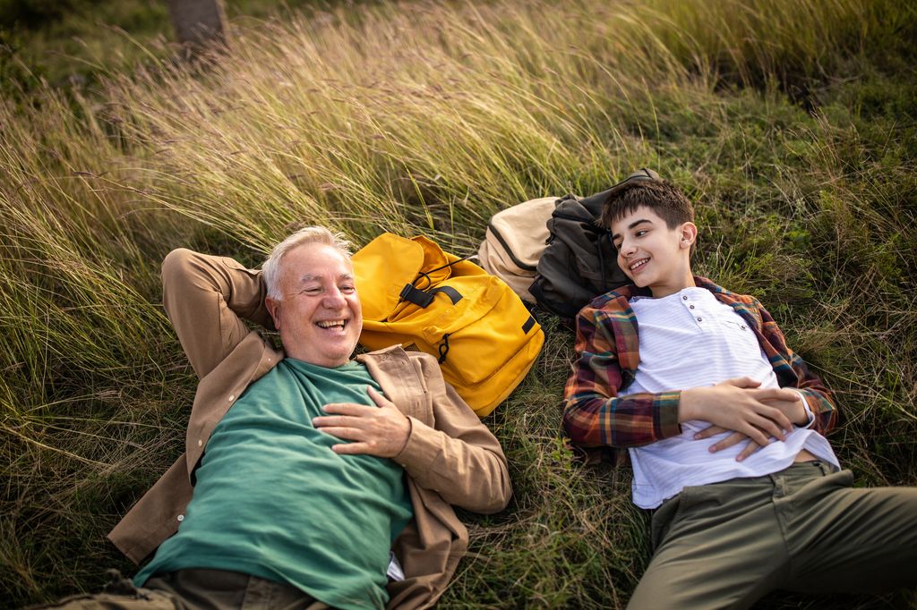 abuelo y nieto tumbados en la hierba, sonrientes
