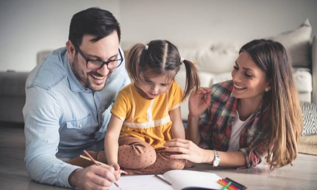 pap s divertidos dibujando en un cuaderno tumbados en el suelo con su hija