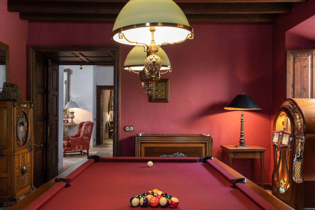 Una sala de juegos con gramola y una mesa de billar como elemento central