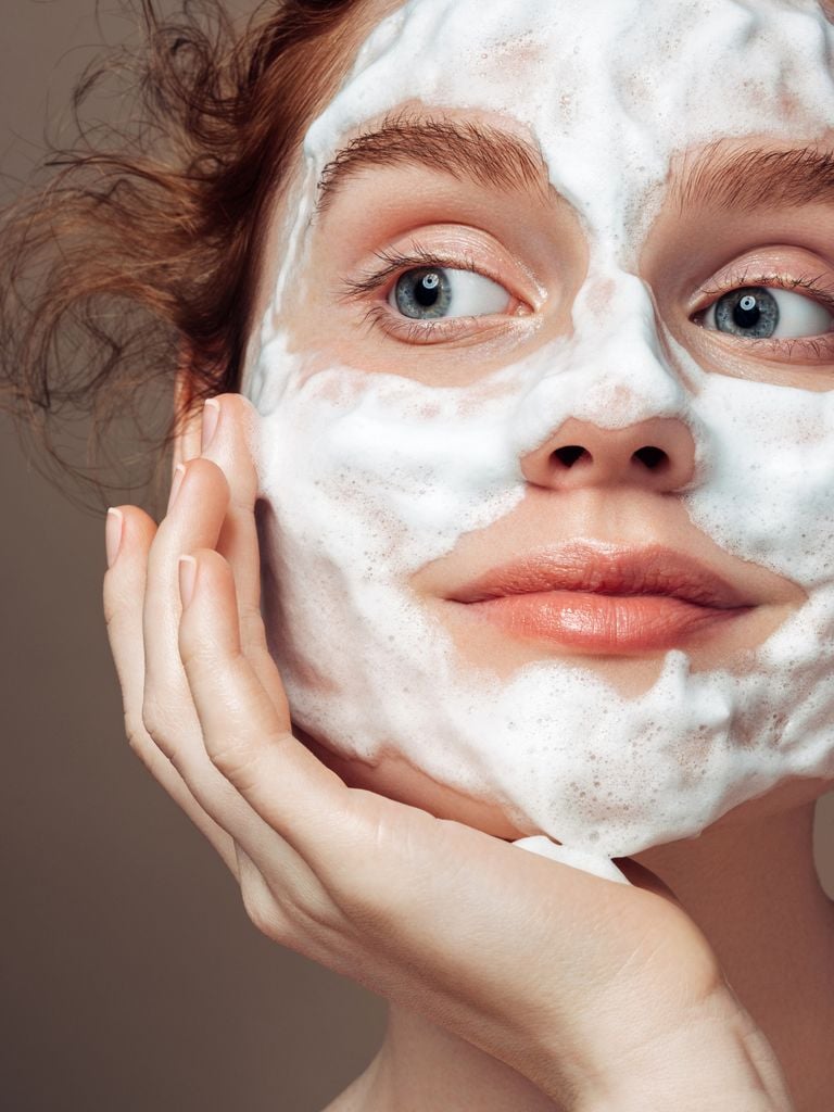 Primer plano mujer con espuma de limpieza en la cara