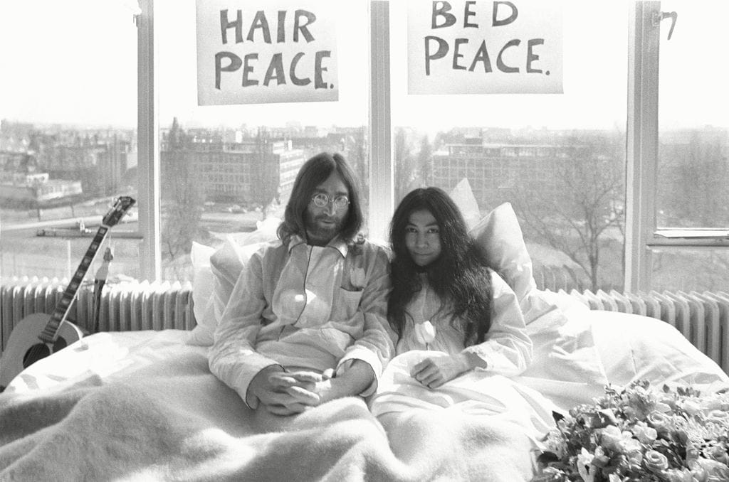 John Lennon y Yoko Ono en una cama con carteles de 'Hair Peace' y 'Bed Peace'.