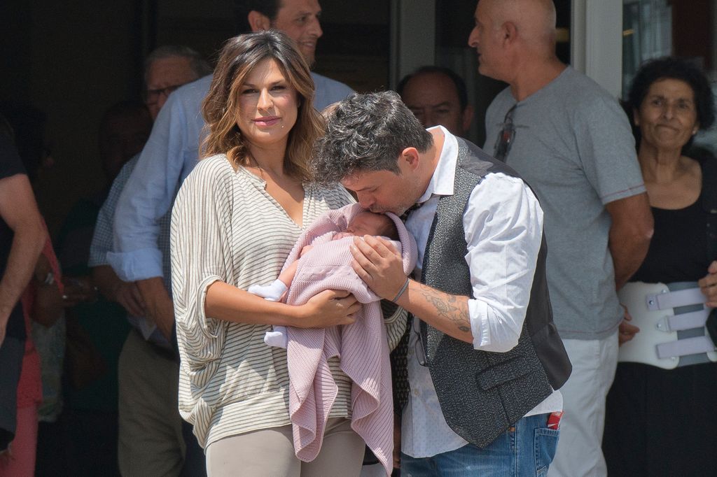 Plano medio de Alejandro Sanz y Raquel Perera saliendo del hospital con su hija Alma
